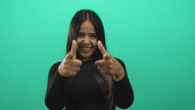 Confident woman shows hands pointing against background in a green latin hispanic isolated smiling portrait. - Powered by Shutterstock - Get 15% off with code: PIKWIZARD15