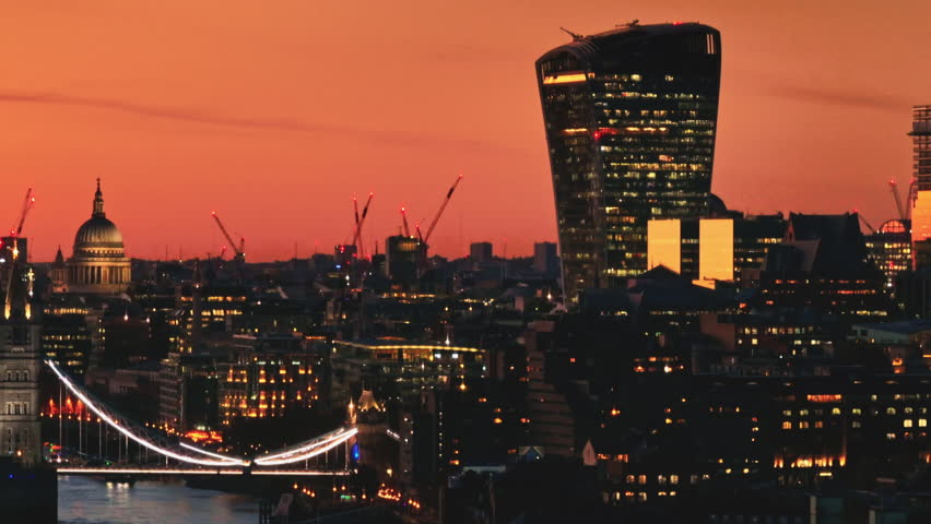 United Kingdom, London: Aerial view capturing the London skyline at sunset, highlighting St. Paul's Cathedral, the Walkie Talkie, and the Millennium Bridge. Drone flight footage