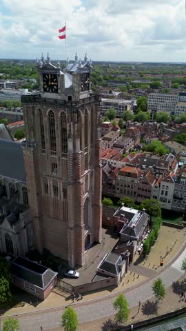 Utrecht, Utrecht region, Netherlands - 09.06.2025: Aerial view of a historic European city with a canal running beneath a clock tower building, red-tiled rooftops, solar panels, and narrow cobblestone