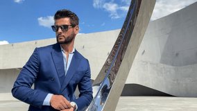 Successful handsome businessman wearing blue suit and sunglasses checking time and look far - Powered by Shutterstock - Get 15% off with code: PIKWIZARD15