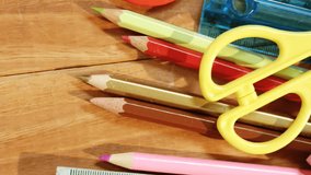 A variety of school supplies are scattered on a wooden surface. Colorful pencils, scissors, and rulers suggest a vibrant school environment, slow motion. - Powered by Shutterstock - Get 15% off with code: PIKWIZARD15