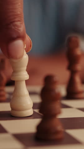 Vertical video,Close-up of a queen chess piece being moved on a chessboard. The focus is on strategy and gameplay, perfect for projects on games, competition, or intelligence.