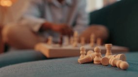 A person plays chess on a couch. The focus is on fallen chess pieces in the foreground, emphasizing loss and defeat. - Powered by Shutterstock - Get 15% off with code: PIKWIZARD15