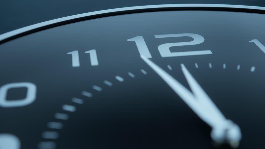 Twelve o'clock on a classic black wall clock. Slow motion, dolly shot, close up.