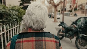 Elderly woman with gray hair walks down the street and touches a green bush. Slow motion. Urban life. - Powered by Shutterstock - Get 15% off with code: PIKWIZARD15