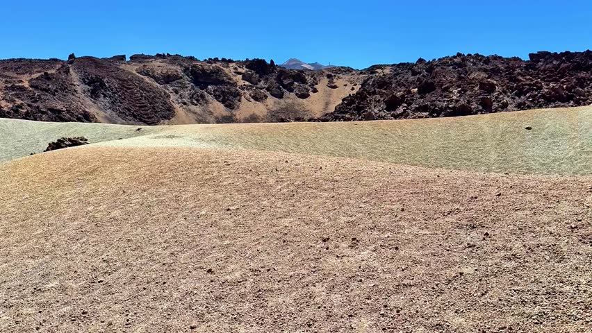 A captivating view of dry hills against a clear blue sky, showcasing rugged terrain and unique formations.