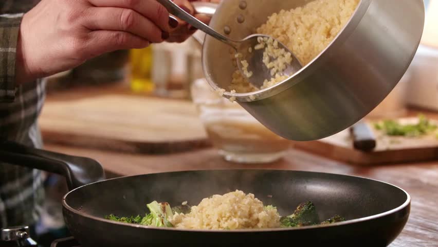 Rice and broccoli are being cooked in a pan