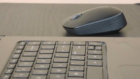 Close-up image showing a person's hand operating a wireless mouse beside a laptop keyboard on a wooden desk. The composition highlights daily digital interaction and technology usage - Powered by Shutterstock - Get 15% off with code: PIKWIZARD15