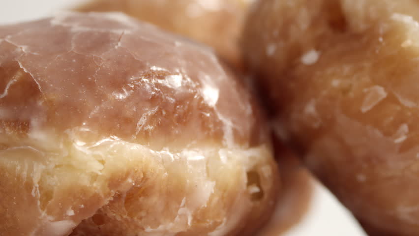 Extreme close-up of brown glazed doughnut with cracked sugar glaze and soft caramel texture, for bakery packaging.