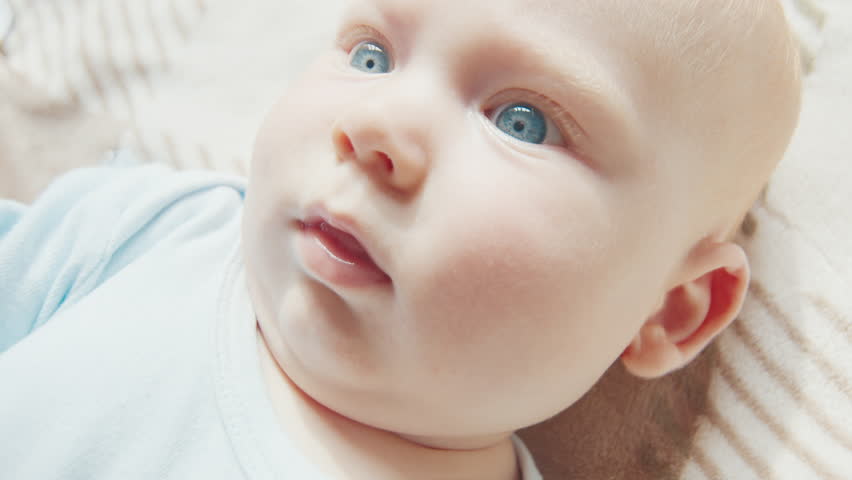 Portrait of the newborn boy (5 months old) with deep blue eyes in the bright white room