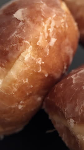 Extreme close-up of rotating glazed donut with cracked sugar coating and warm highlights, for pastry commercial detail shot.
