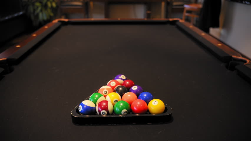 Player breaking racked pool balls in eight ball formation on pool table for start to play. Slow motion