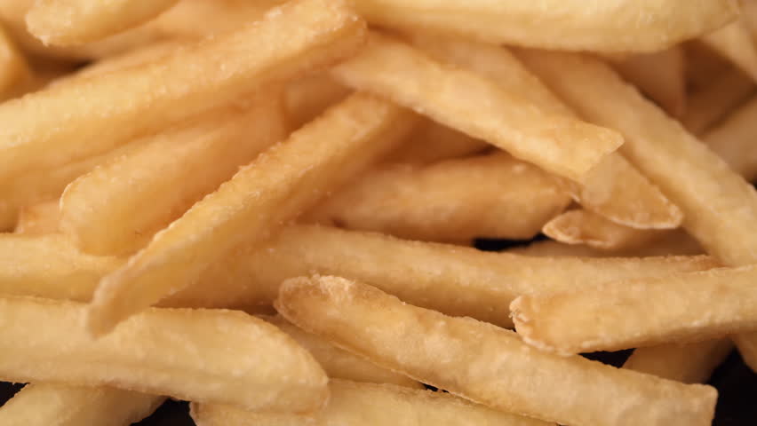 Extreme close-up of rotating matte fries with soft texture and crispy edges, for food packaging.