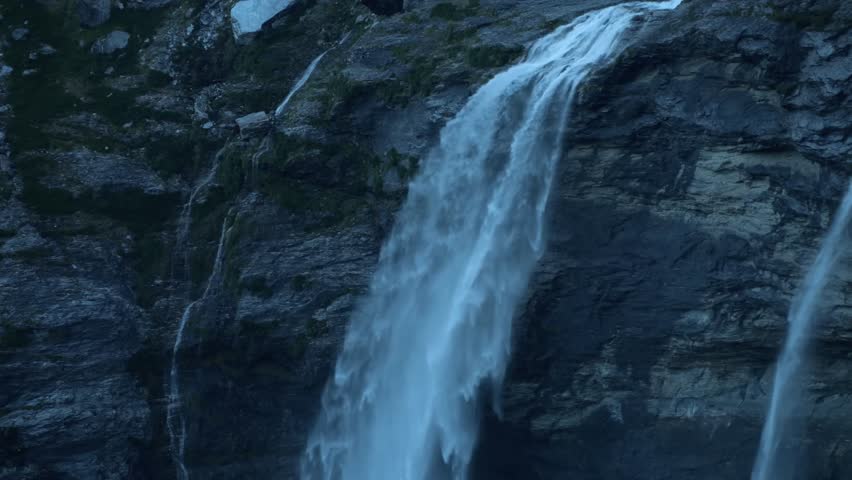 A dynamic video capturing a natural spring water rushing powerfully down the mountain slope like a waterfall.