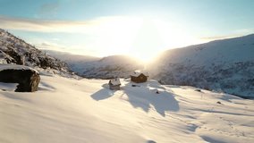 A breathtaking drone shot of a pristine snow-covered winter landscape featuring two rustic wooden cabins with smoke rising from a chimney. - Powered by Shutterstock - Get 15% off with code: PIKWIZARD15