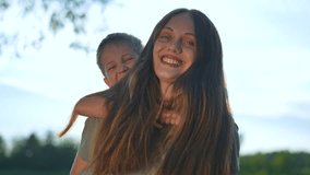 Mother giving child piggyback ride park. Smiling child enjoying playful moment mother outdoors. Joyful family time, mother bonding with child in park. Happy child and mother piggyback ride in nature. - Powered by Shutterstock - Get 15% off with code: PIKWIZARD15