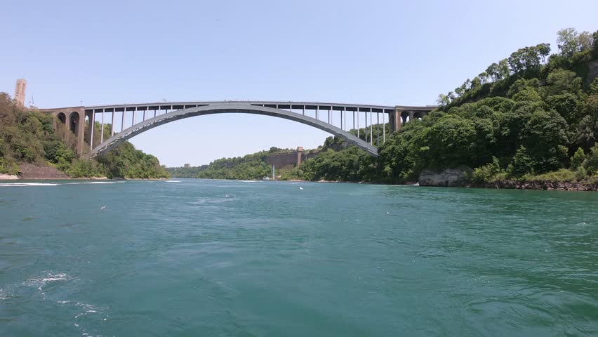 The Niagara Falls International Rainbow Bridge, a steel arch bridge across the Niagara River, connecting the cities of Niagara Falls, New York, and Niagara Falls, Ontario, seen from a boat tour.
