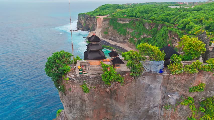 Bali's Most Iconic Landmark and popular tourist attraction Uluwatu Temple one of six key Bali temple perched on top mountain cliff on background amazing nature Bali, Indonesia. 4K Aerial view