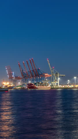 Night timelapse of Hamburg cargo port, showcasing container terminals, cranes and cargo ships on the Elbe River. Boats and vessels pass by, creating a dynamic maritime panorama. Germany