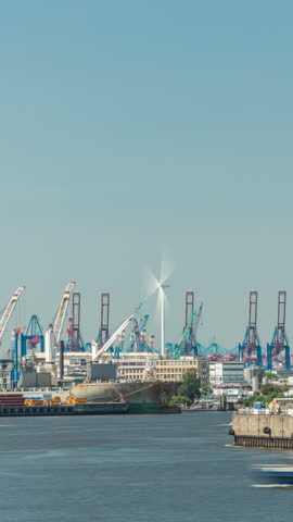 Timelapse of Hamburg cargo port, showcasing container terminals, cranes and cargo ships on the Elbe River. Boats and vessels pass by modern buildings, creating a dynamic maritime panorama. Germany