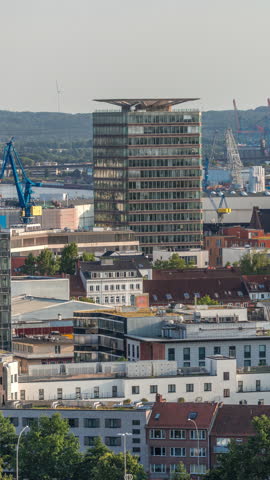 Aerial skyline timelapse of Hamburg with modern office towers and residential buildings, warm evening light, cranes in cargo port and urban panorama from bunker rooftop, Germany