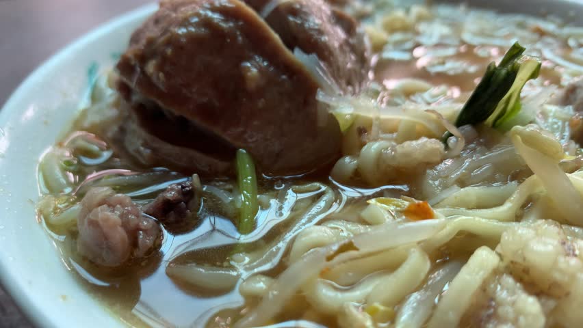 4K close-up of Indonesian bakso meatball soup with spicy sambal. Warm, flavorful mood, focused on texture and taste. Ideal for food, culture, and culinary storytelling concepts.