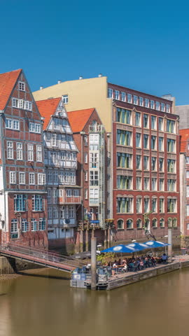 Aerial timelapse of Kleines Dock along the northern Elbe Canal in Hamburg, Germany. Picturesque cafes and historic brick houses line the serene waterfront, perfect for dining or enjoying tidal views