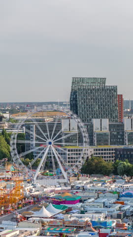 Aerial skyline timelapse of Hamburg with modern office and residential buildings, warm evening light, cranes in cargo port and urban panorama from bunker rooftop. Attraction with ferris wheel. Germany