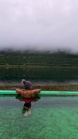 A woman unwind in a geothermal hot spring in Iceland, where serene waters meet stunning mountain landscapes. The perfect escape for relaxation, Hot pool, Westfjords, Iceland