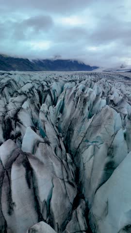 Majestic ice formations and deep crevasses create a stunning landscape at Skaftafell Glacier. This captivating location in Iceland showcases natures artistry during an overcast day.