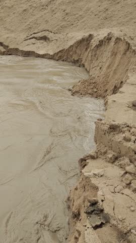 Eroded riverbank muddy water sand erosion natural landscape outdoor environmental impact overcast eroded sandbank muddy water