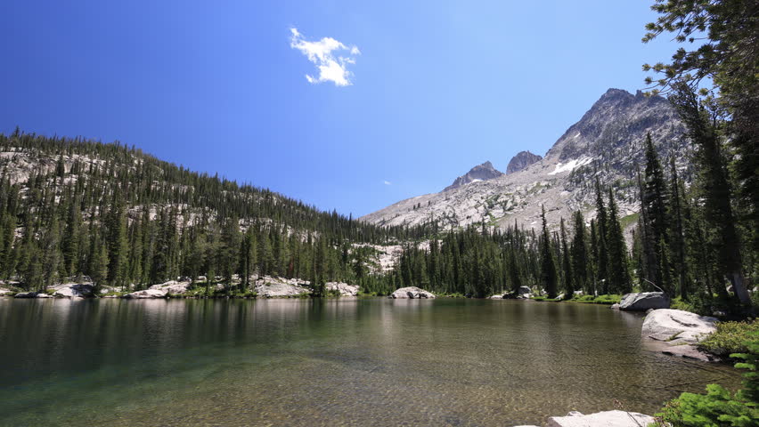Toxaway Lake on a clear summer day, with views toward Snowyside Pass and the rugged surrounding peaks of the Sawtooth Mountains.