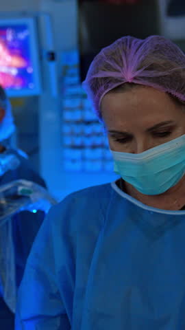 Professional scrub nurse wearing uniform. Portrait of a medic working in modern surgery room with Da Vinci Robot. Vertical video.