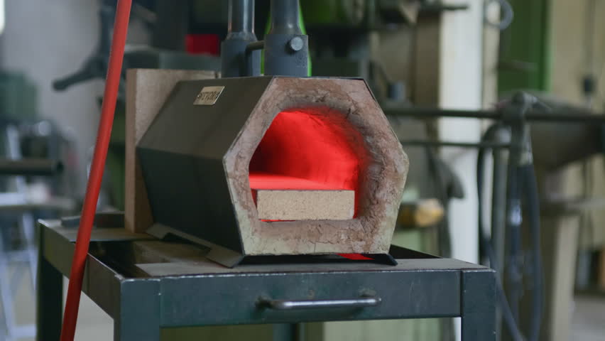 Cooling blacksmith forge after use, with faint red glow fading in the dark. Captures the end of a work session, heat dissipation, and the quiet atmosphere of the workshop.