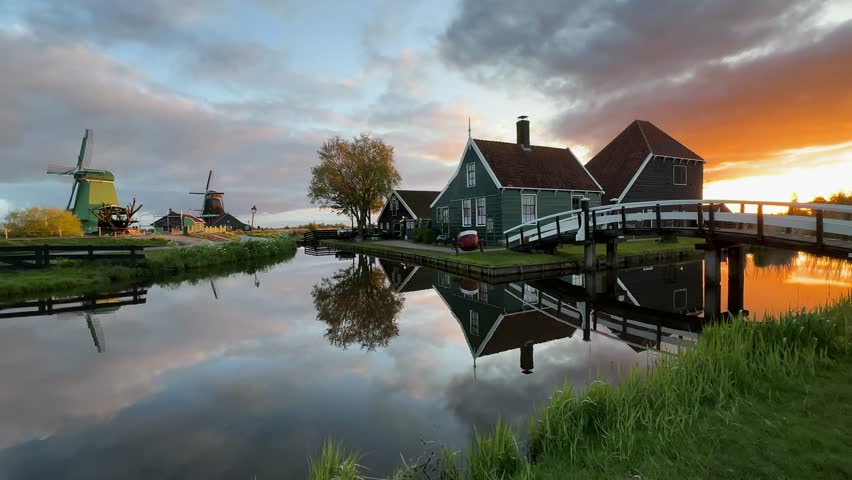 traditional Dutch windmills of Zaanse Schans over water at summer sunset, Netherlands