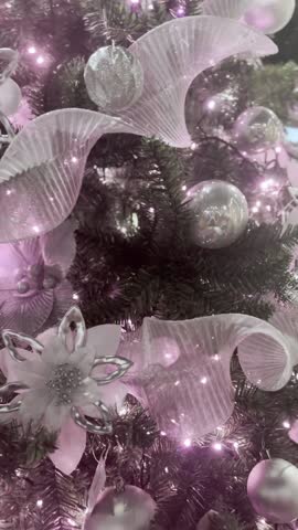 Two hands hang a star of Bethlehem on a Christmas tree decorated with many ornaments.