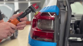 A man polishes a taillight, a car headlight with a polishing machine. The concept of polishing car paintwork. The car wax polishing process. The process of polishing the taillights. - Powered by Shutterstock - Get 15% off with code: PIKWIZARD15