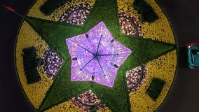 4K top-down drone shot rising vertically from the center of an illuminated floral roundabout at night. Captured in Vietnam, showcasing geometric symmetry and vibrant neon colors. - Powered by Shutterstock - Get 15% off with code: PIKWIZARD15