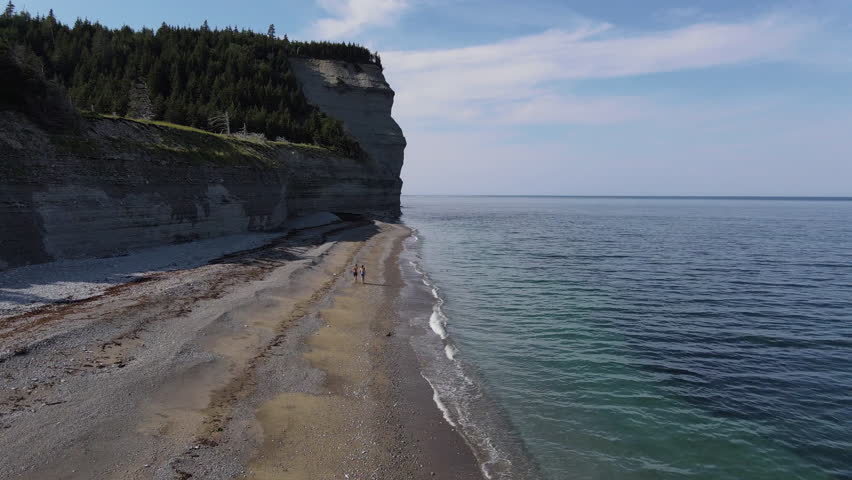 Aerial View of  People Walking on the Pebble Beach Next to Turquoise Waters in Easton Bay, on Anticosti Island, Quebec, Canada