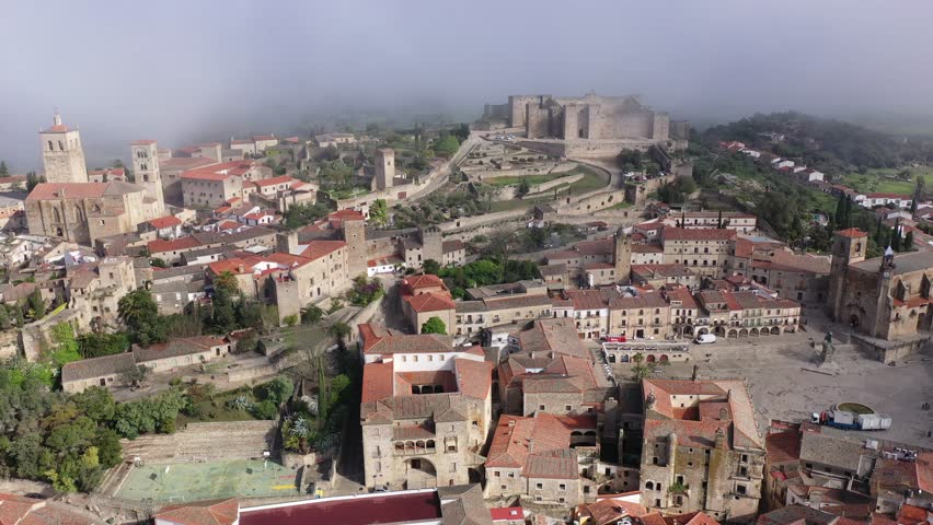 Scenic drone view of old town of Trujillo with Plaza Mayor, ancient Alcazaba and Temple of Santa Maria in fog on spring day, Extremadura, Spain. High quality 4k footage
