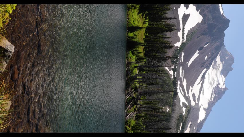 Crystal-clear Scout Lake reflecting the deep blue sky and snow-covered Mount Jefferson in Mount Jefferson Wilderness, Oregon, USA. Peaceful alpine scenery surrounded by forest and rocky shoreline