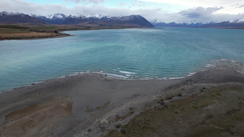 Lake Tekapo In South Island Of New Zealand - Turquoise Lake With Waves Splashing On Sandy Shore. drone shot