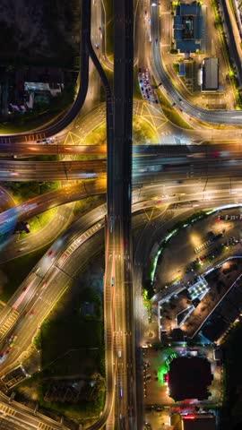 Aerial timelapse of busy multilane highway interchange in Kuala Lumpur, Malaysia at night. Illuminated roads, traffic, and overpasses in modern urban infrastructure.
