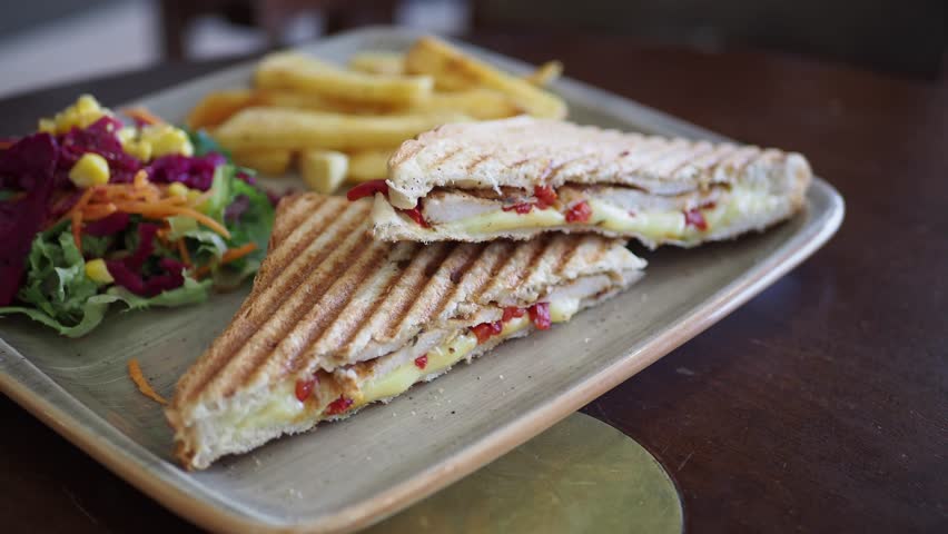 Delicious sandwich with salad and fries served in cozy cafe setting