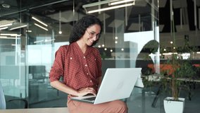 Happy young businesswoman working on laptop computer sitting at a desk in business office. Smiling female employee happily completing a task, chatting online with a colleague or browsing social media - Powered by Shutterstock - Get 15% off with code: PIKWIZARD15