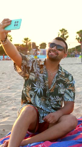 Group of diverse friends sharing joyful moments, capturing selfie while enjoying sunset beach picnic with snacks, fresh fruit, and drinks during summer vacation