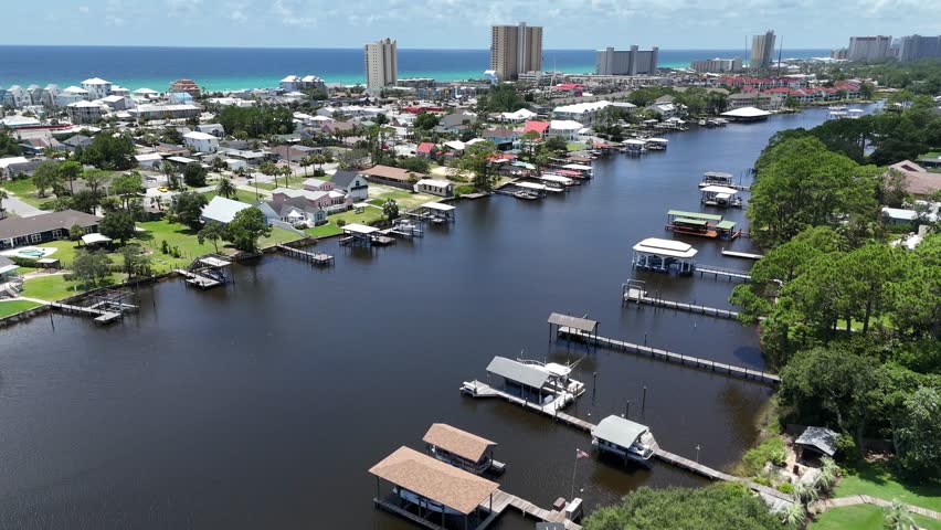 Dynamic backwards drone movement over inland waterway on residential area with docks, Panama City Beach, Florida, USA