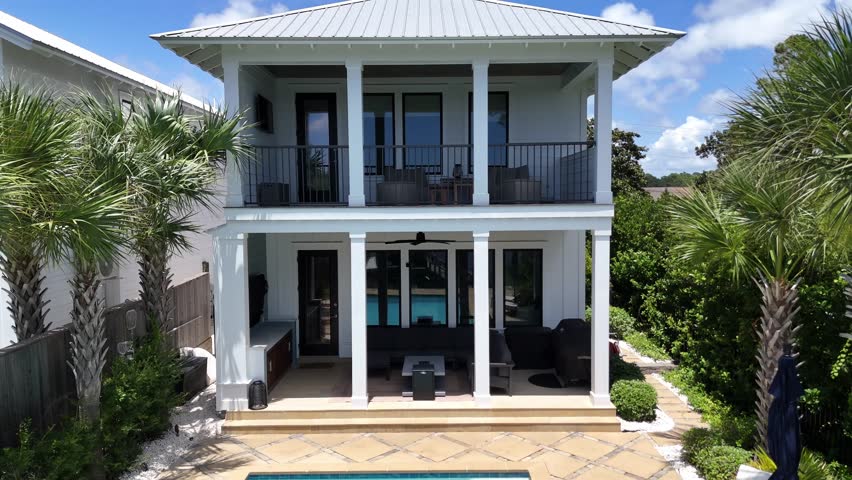 Backwards drone movement from a modern luxury house with swimming pool and backyard in sunny suburb of Panama City Beach, Florida, USA