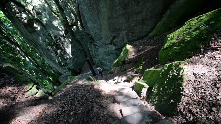 Female hiker exploring the Rock formations at Berdorf in Luxembourg during summer on Mullerthal hiking trail	