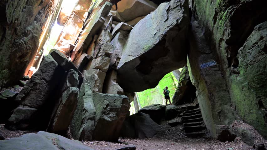 Female hiker exploring the Rock formations at Berdorf in Luxembourg during summer on Mullerthal hiking trail	
